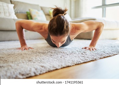 Woman With Bent Arms Making Pushups At Home Looking Down