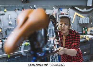 Woman bicycle engineer is repairing a bike in the workshop. Bicycle mechanic in a workshop in the repair process. Technical expertise taking care Bicycle Shop - Powered by Shutterstock