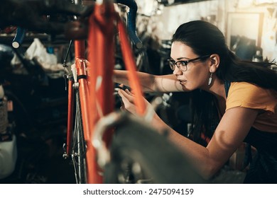 Woman, bicycle mechanic and fix with inspection for maintenance or small business at repair shop check. Young female person or cycling engineer working on bike with tools or equipment at workshop - Powered by Shutterstock