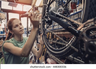 Woman Bicycle Mechanic Is Repairing A Bike In The Workshop 