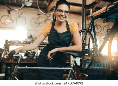 Woman, bicycle shop and portrait for maintenance job, startup with transport service. Bike, mechanic and female entrepreneur in workshop with glasses, happiness for sustainable business with apron - Powered by Shutterstock