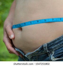 Woman With Big Belly. Jeans That Don't Fit Any More. Measuring The Waist With Tape Measure.