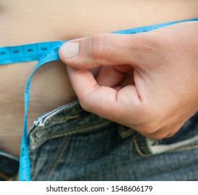 Woman With Big Belly. Jeans That Don't Fit Any More. Measuring The Waist With Tape Measure.