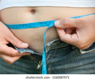 Woman With Big Belly. Jeans That Don't Fit Any More. Measuring The Waist With Tape Measure.