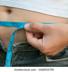 Woman With Big Belly. Jeans That Don't Fit Any More. Measuring The Waist With Tape Measure.