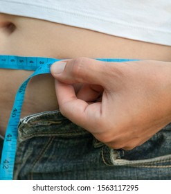 Woman With Big Belly. Jeans That Don't Fit Any More. Measuring The Waist With Tape Measure.