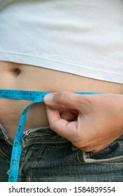 Woman With Big Belly. Jeans That Don't Fit Any More. Measuring The Waist With Tape Measure.