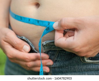 Woman With Big Belly. Jeans That Don't Fit Any More. Measuring The Waist With Tape Measure.