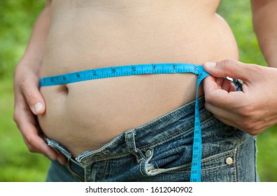 Woman With Big Belly. Jeans That Don't Fit Any More. Measuring The Waist With Tape Measure.