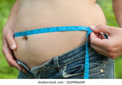 Woman With Big Belly. Jeans That Don't Fit Any More. Measuring The Waist With Tape Measure.