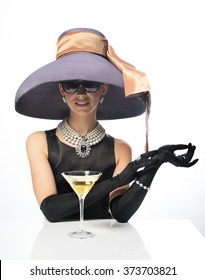 A Woman In A Big Hat And Sunglasses, Like A Movie Star, Drinking Martinis