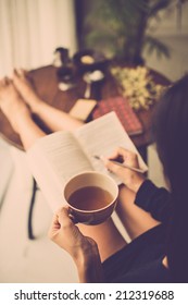 Woman With Big Mug Of Tea Reading A Book And Making Notes