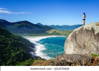Woman in a big rock looking at Praia do Bonete (Bonete Beach) in Ilhabela (Beautiful Island), São Paulo, Brazil 