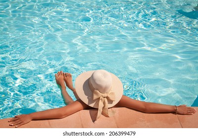 Woman In Big Straw Hat Relaxing On The Swimming Pool. Girl At Travel Spa Resort Pool. Summer Luxury Vacation.