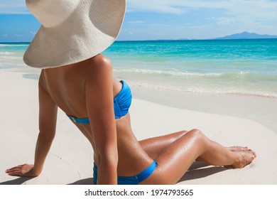 Woman In Big Sun Hat Sitting On Beach By The Sea Side View