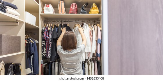 Woman In Big Walkin Closet Choosing Clothes. Modern Wardrobe And Dressing Room With Copy Space