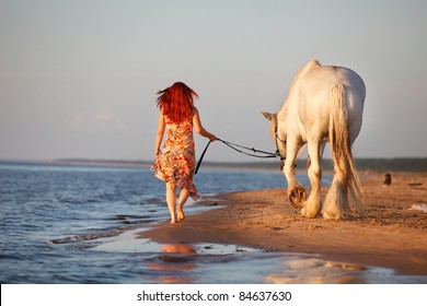 Woman with big white horses going along seashore - Powered by Shutterstock