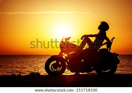 Woman biker enjoying sunset, female riding motorcycle, motorbike driver traveling the world, girl resting on the beach road, freedom lifestyle