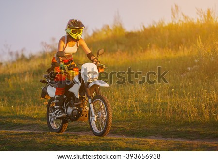 Woman biker rides in fields. Sporty woman biker at motobike. Countryside, country road.  sunset, female motorcycle rider, motorbike rider traveling the world, girl resting, freedom lifestyle