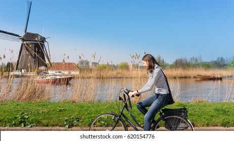 Woman bikes along windmill