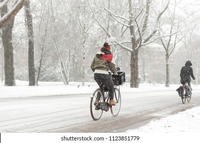 A woman biking in the Amsterdam Vondelpark on a snowy winter day in december in the Netherlands.