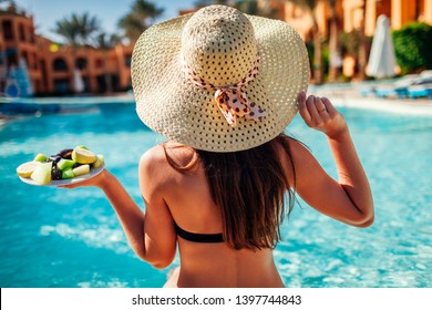 Woman In Bikini Eating Fruits And Relaxing In Swimming Pool. All Inclusive Concept. Summer Vacation