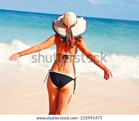 Woman in bikini and hat on tropical beach