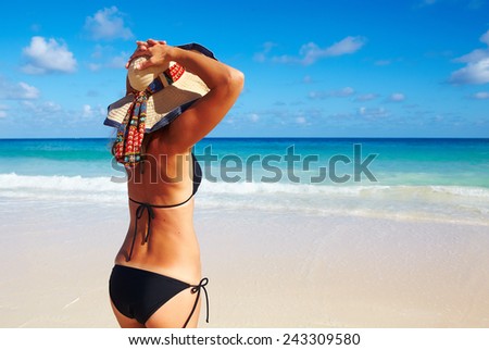 Woman in bikini and hat on tropical beach