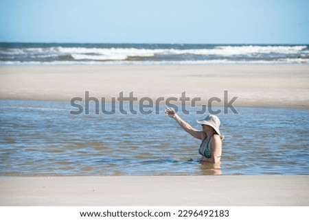 Woman in a bikini and hat relaxing in the sea. Taquari, Guaibim beach, Valenca, Bahia.