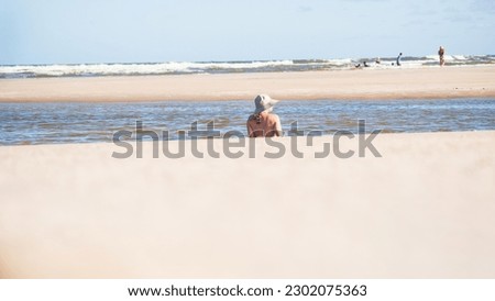 Woman in a bikini and hat relaxing in the sea. Taquari, Guaibim beach, Valenca, Bahia.