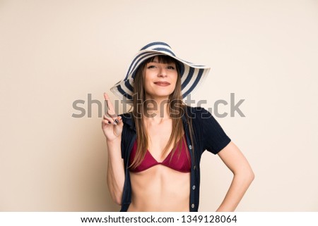 Woman in bikini on ocher background pointing with the index finger a great idea
