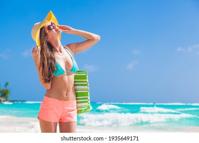 woman in bikini and with straw bag relaxingon tropical beach. Maldives