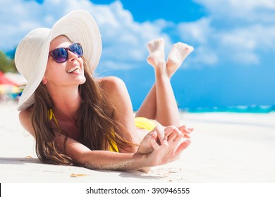 woman in bikini and sun hat relaxing at sunny beach. remote tropical beaches and countries. travel concept