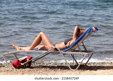 Woman In Bikini Sunbathing In Lounge Chair On Sea Background. Beach Vacation, Summer Leisure And Travel