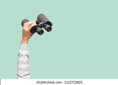 Woman with binoculars on green background, looking through binoculars, journey, find and search concept.