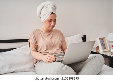 Woman With Bionic Limb Is Sitting On Bed And Looking At The Screen Of The Laptop