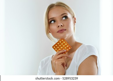Woman With Birth Control Pills. Healthy Beautiful Girl Holding Blister Pack With Oral Contraceptive Pills In Hand And Thinking Should She Take A Pill. Medicine, Health Care Concept. High Resolution