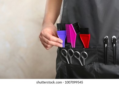 Woman in black apron with professional hairdresser set on light background, closeup - Powered by Shutterstock