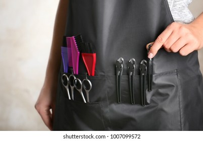 Woman In Black Apron With Professional Hairdresser Set On Light Background, Closeup