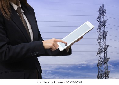 Woman with black blazer and silver necktie pointing her finger on tablet withb power line in blue sky as background - Powered by Shutterstock