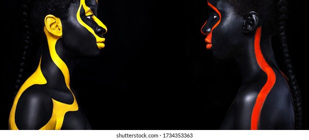 Woman with black body paint. Cheerful young african girl with art bodypaint. An amazing model with yellow and red makeup. Closeup face with copy space.
