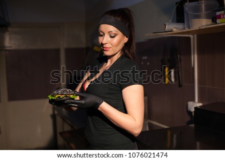 woman in black chef prepares a burger in a restaurant