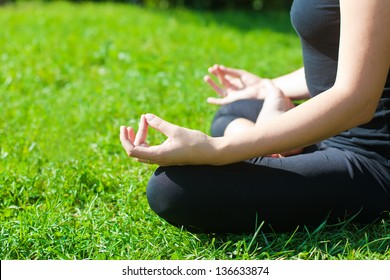 Woman In Black Clothes Practicing Yoga Outside, On A Grass