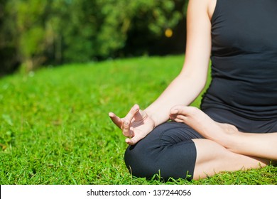 Woman In Black Clothes Practicing Yoga Outside, On A Grass