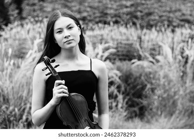 Woman in black dress holding a violin, suitable for music events promotion. - Powered by Shutterstock