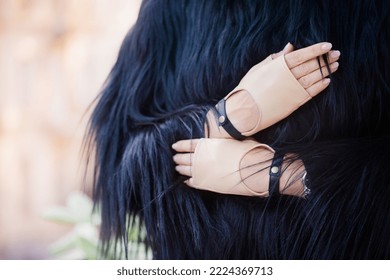 A Woman In A Black Fur Coat And Beige Gloves Mittens