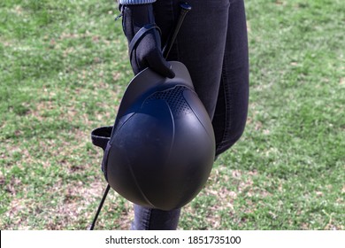 Woman In Black Gloves Holding Horse Back Riding Helmet And Whip In Her Hands. Equestrian Equipment