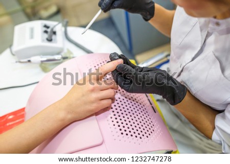 woman in black gloves in the salon makes manicure to the client