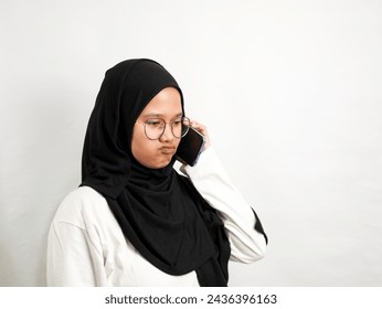 woman in black hijab with a sour face sullen when receiving the phone