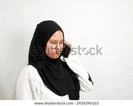 woman in black hijab with a sour face sullen when receiving the phone